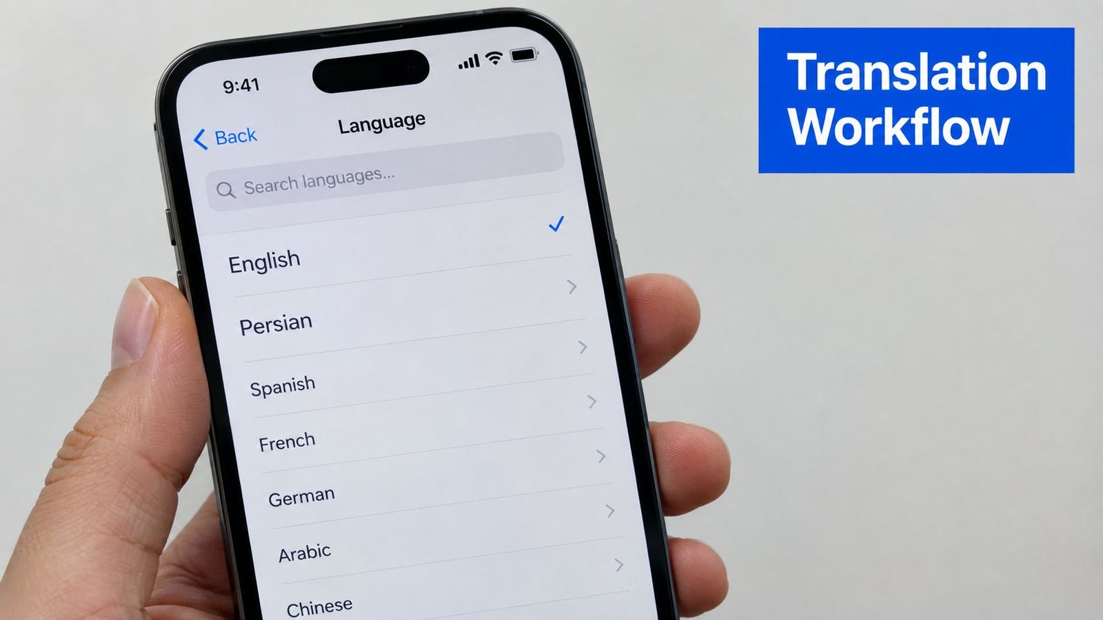 A hand holding a smartphone displaying a language settings menu with English and other languages listed.